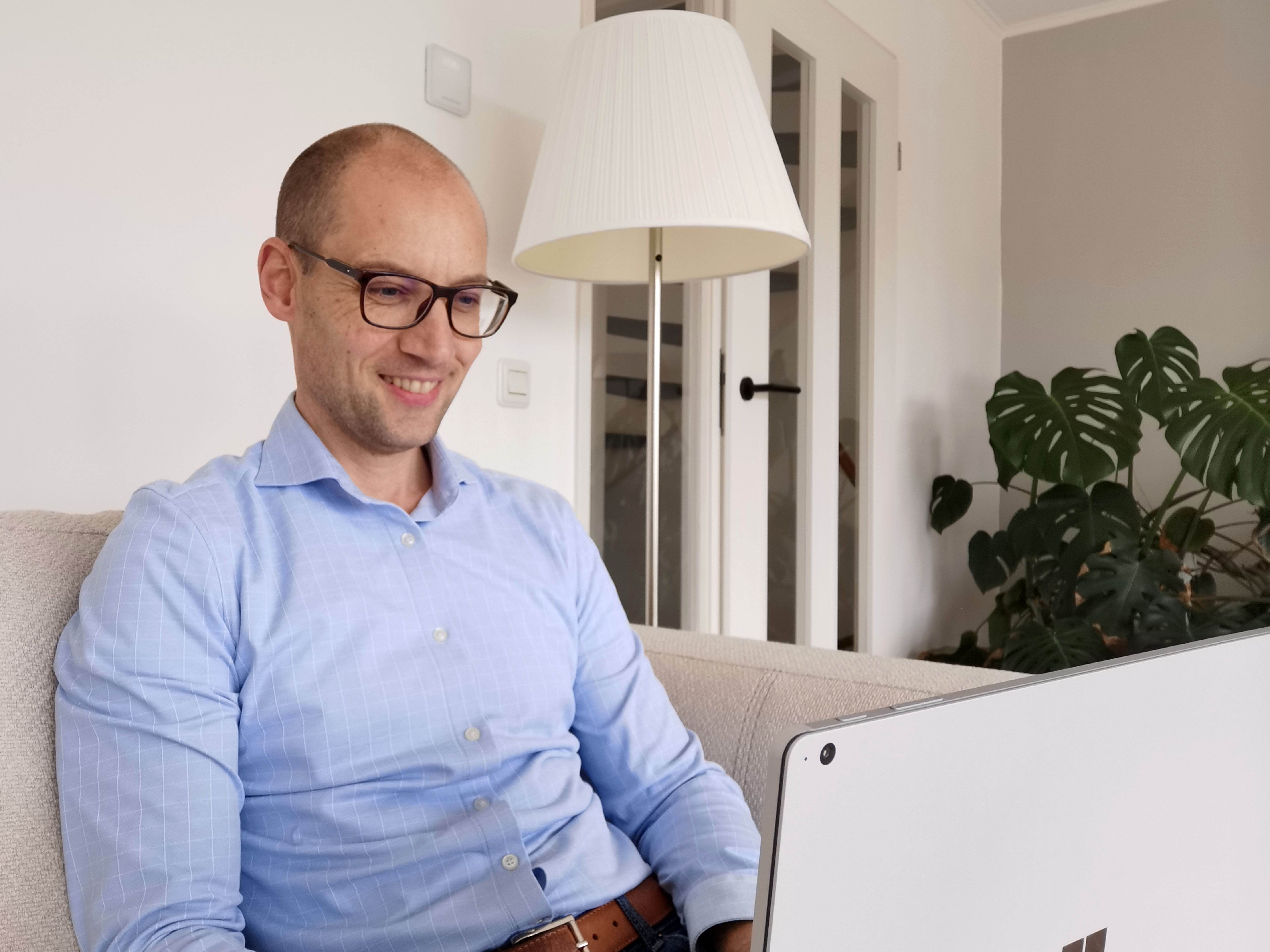 Michiel Kox zitten op de bank met een laptop op schoot
